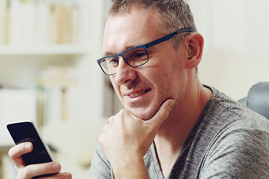 Person using smartphone with modern hearing aids